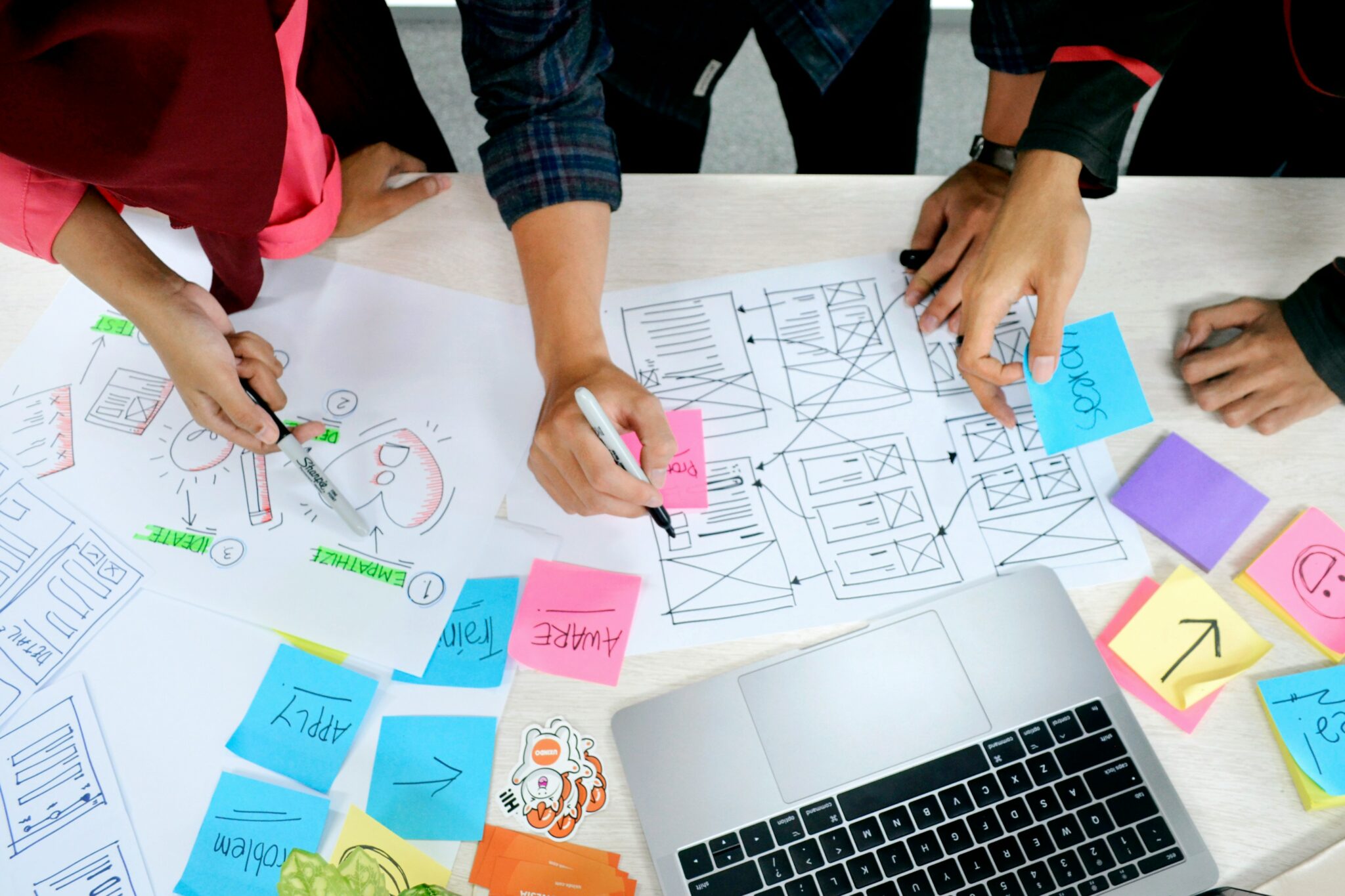 A team collaboratively working on a laptop, surrounded by colorful sticky notes, brainstorming ideas and fostering creativity.